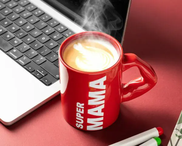 Kubek „Super Mama” z gorącą kawą i pianką na tle laptopa